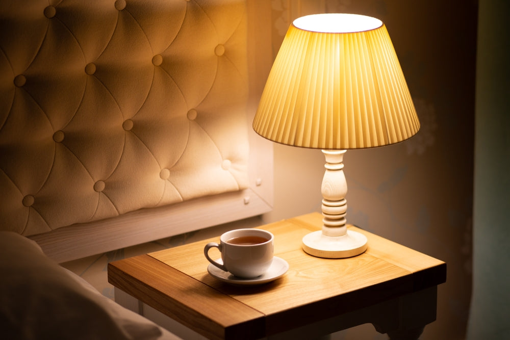 Person reading in bed with the help of a lamp